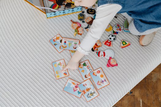 A child engaging with educational flashcards and colorful stickers on a bed.