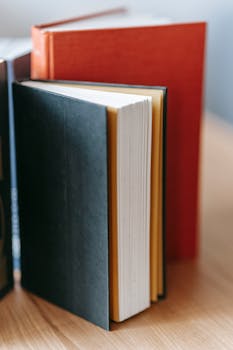 Close-up of colorful hardcover books standing upright on a wooden surface.