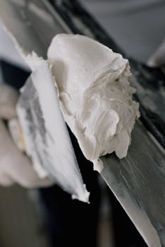 Detailed image of a trowel applying plaster in a construction setting, focusing on texture and technique.