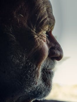 Close-up side view portrait of a thoughtful senior man with wrinkles and beard, emphasizing age and wisdom.